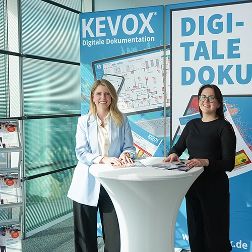 Zwei Mitarbeiterinnen von KEVOX am Messestand mit Informationsmaterial zur digitalen Dokumentation.