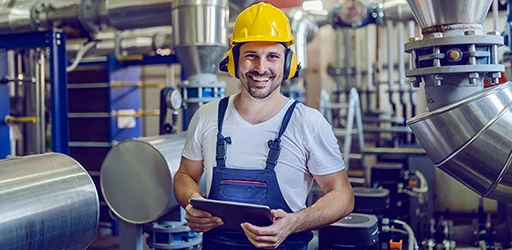 Techniker mit gelbem Schutzhelm und Tablet in einer Industrieanlage.