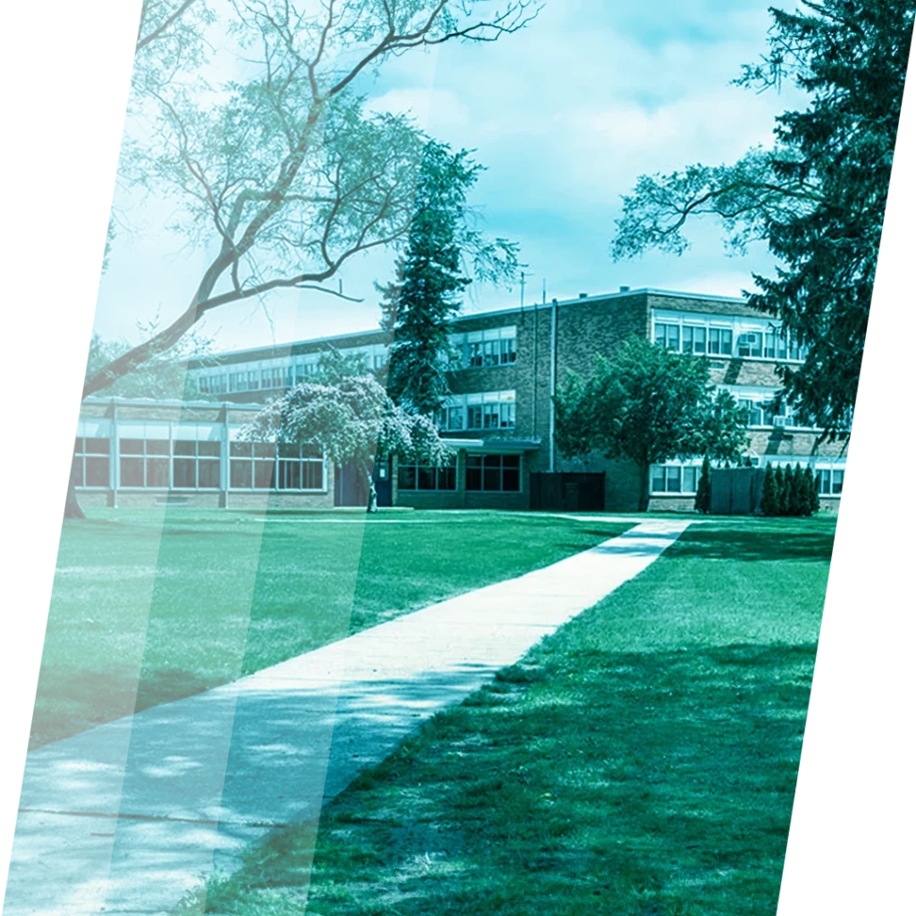 Schulgebäude mit gepflegtem Rasen und Fußweg auf dem Campus.