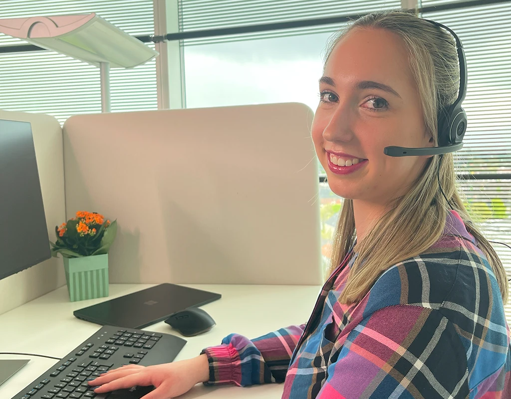 Mitarbeiterin bei KEVOX mit Headset am Arbeitsplatz.