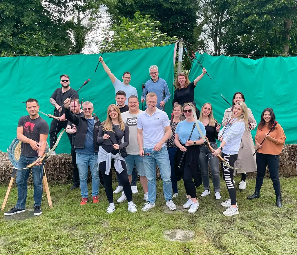 Gruppenfoto des KEVOX Teams bei einem Teamevent mit Bogenschießen im Freien.